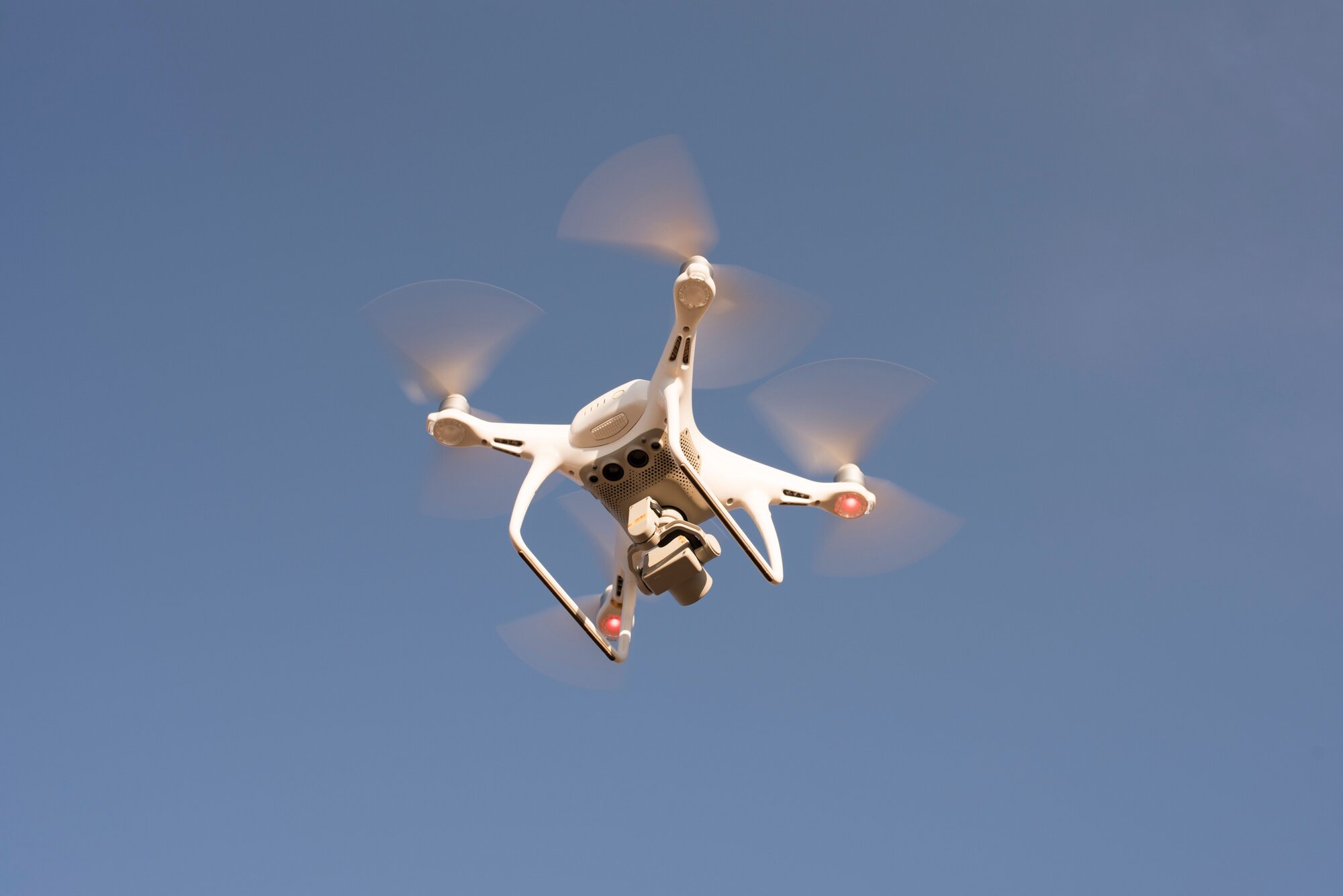 A camera drone in flight against a clear sky