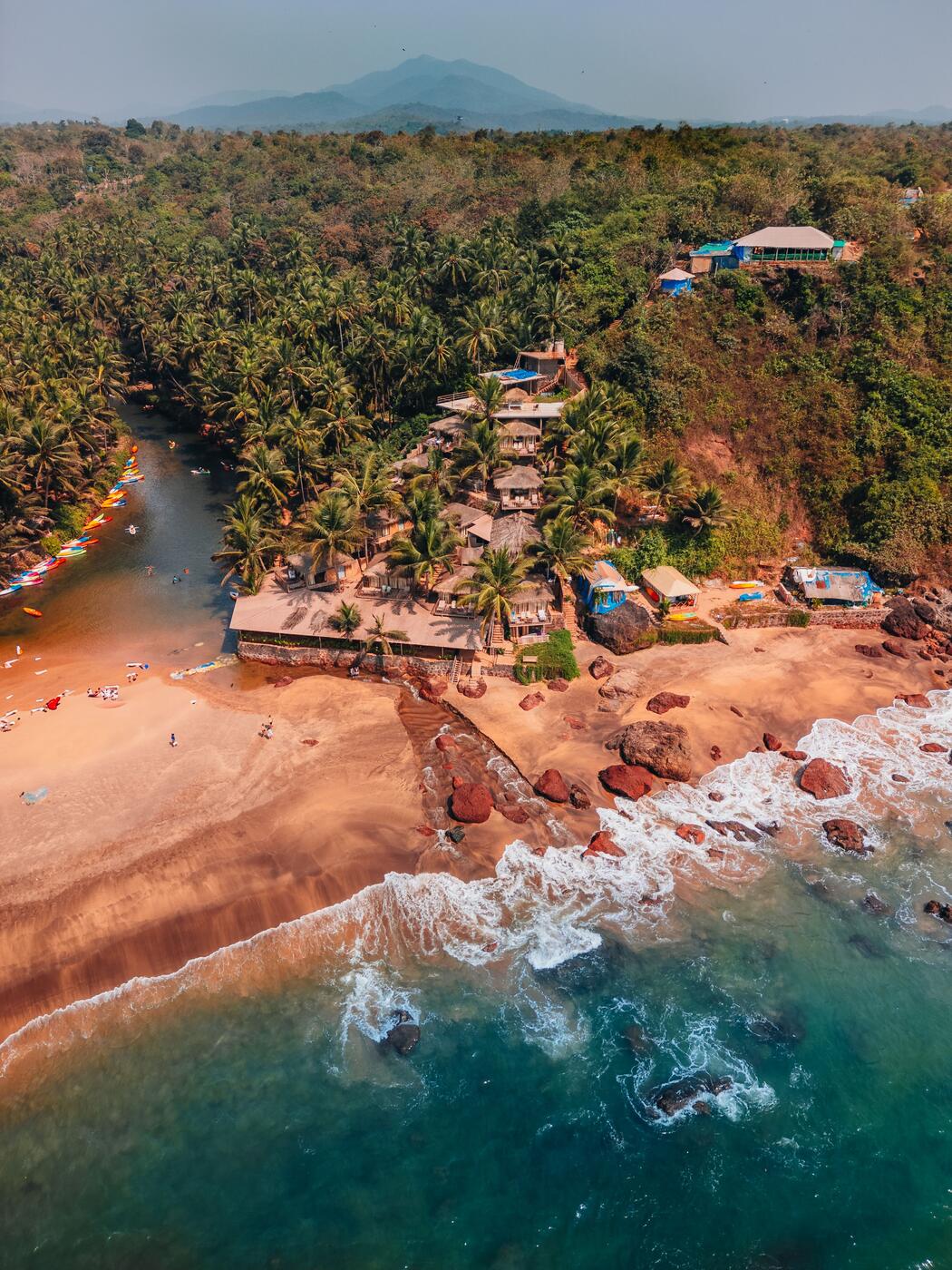 Aerial view of beach shacks and surf on the Goa coastline